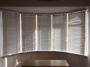 Cream wooden venetian blinds in 5 sided bay window